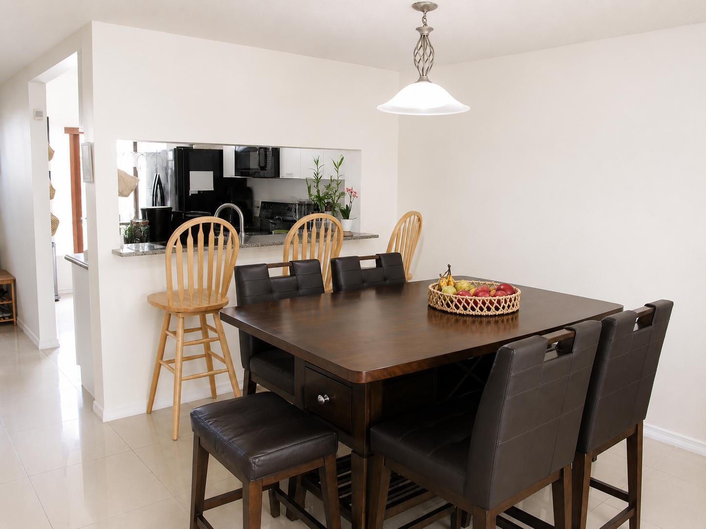 A dining area with a dark wood table, upholstered chairs, and a kitchen pass-through window — 75 Whitehead Circle # 75, Weston FL 33326, WESTON, FL