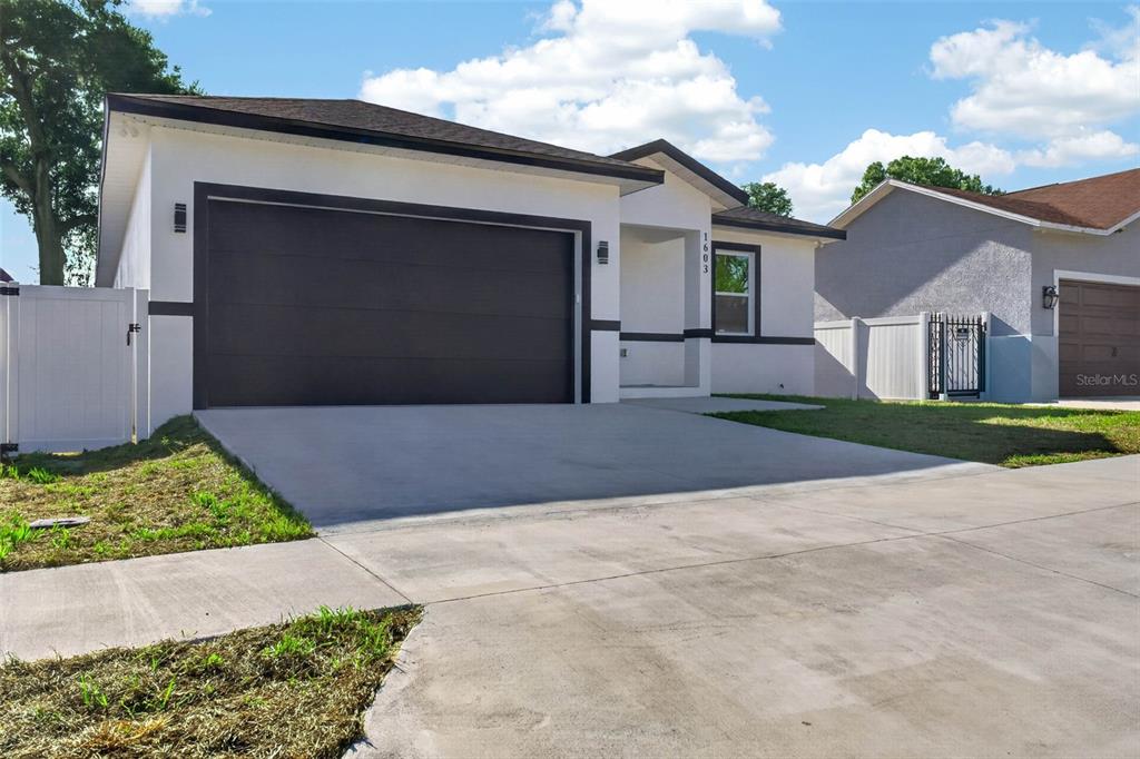 A single-story house with a white exterior, dark trim, and a two-car garage — 1603 WRIGHT DRIVE, LAKELAND, FL