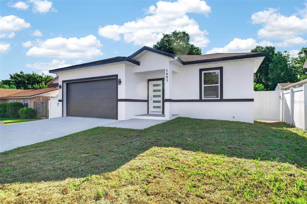 A white single-story house with a dark garage door and a front entrance — 1603 WRIGHT DRIVE, LAKELAND, FL