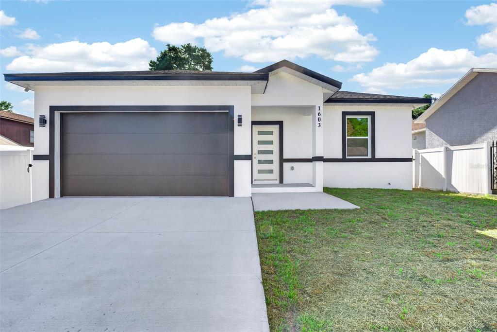 A single-story house with a white exterior, dark trim, a garage, and a front entrance — 1603 WRIGHT DRIVE, LAKELAND, FL