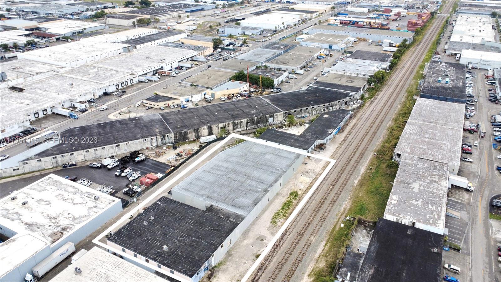 An aerial view shows a commercial warehouse building with a flat roof next to railroad tracks — 7000 NW 37th Ct, Hialeah FL 33147, HIALEAH, FL