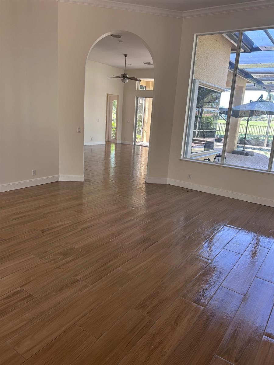 A bright living area features wood-look tile flooring, an arched entryway, and large windows — 8992 Lakes Boulevard, West Palm Beach FL 33412, WEST PALM BEACH, FL