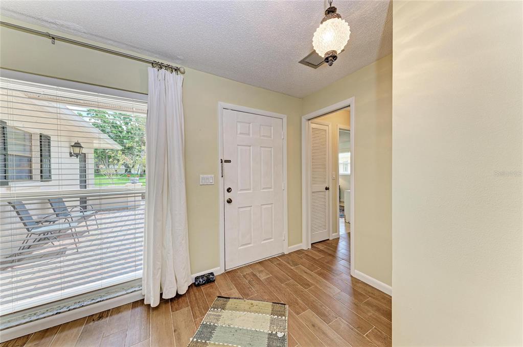 An entryway with wood-look tile flooring, a white front door, and a large window — 7160 FAIRWAY BEND CIR, SARASOTA, FL