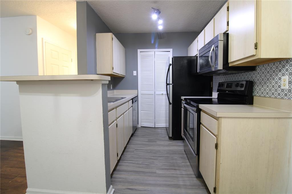 A galley kitchen features light wood cabinets, black appliances, gray walls, and patterned backsplash tile — 4348 S KIRKMAN ROAD UNIT 813, ORLANDO, FL