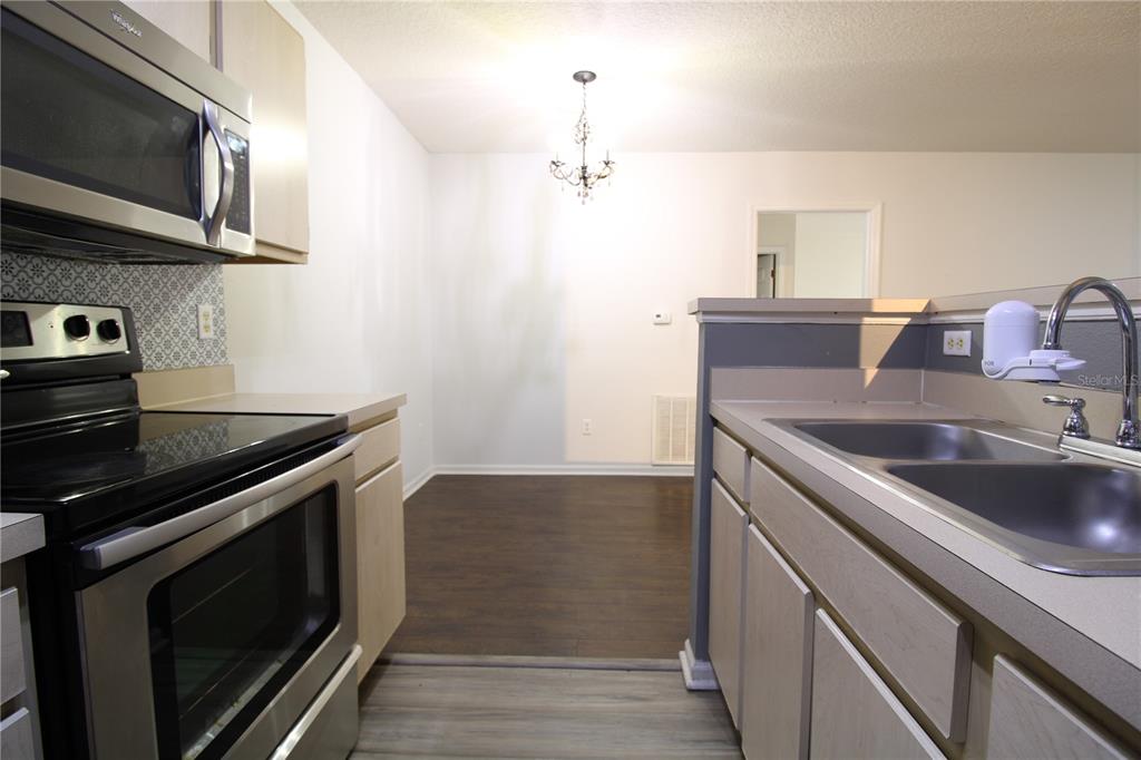A kitchen with light wood cabinets, stainless steel appliances, and a view into a dining area — 4348 S KIRKMAN ROAD UNIT 813, ORLANDO, FL