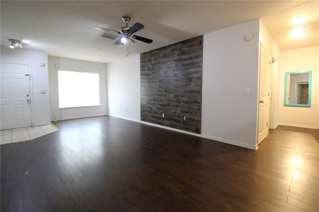 A living room features dark wood-look flooring, a ceiling fan, and a wood-paneled accent wall — 4348 S KIRKMAN ROAD UNIT 813, ORLANDO, FL