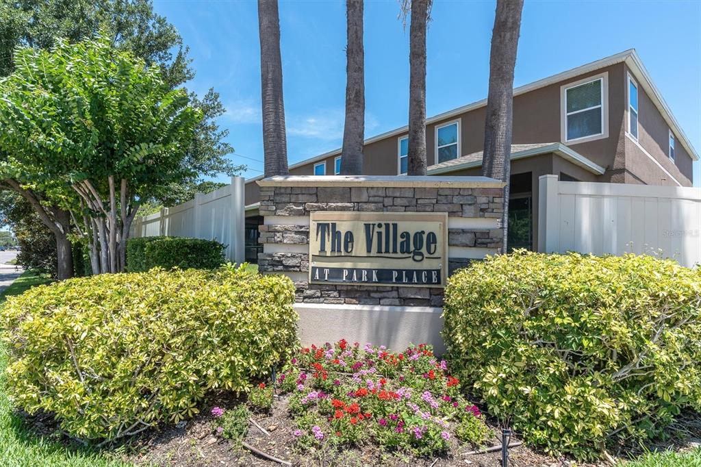 A stone monument sign for The Village at Park Place stands before a multi-story building — 4057 71ST TERRACE N, PINELLAS PARK, FL