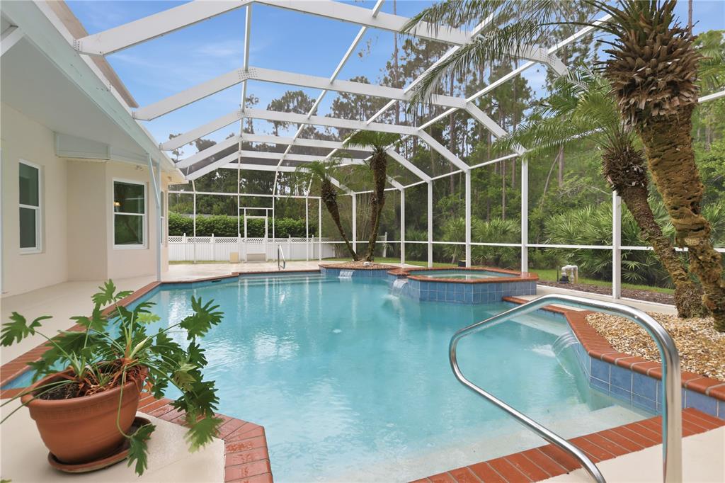 A screened-in swimming pool and spa area with brick coping and surrounding palm trees — 3 ALLENWOOD LOOK, ORMOND BEACH, FL