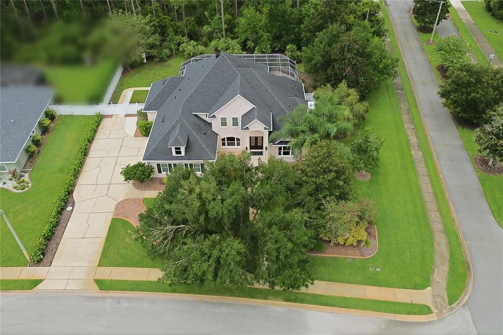 An aerial view shows a two-story house with a dark roof, driveway, and screened-in pool — 3 ALLENWOOD LOOK, ORMOND BEACH, FL