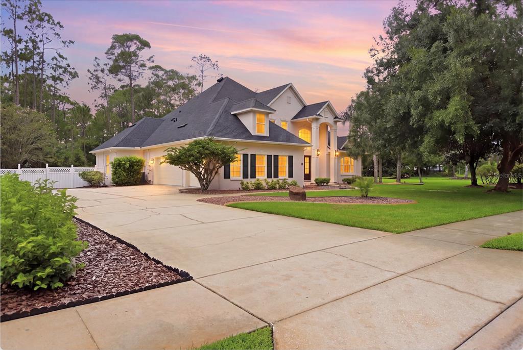 A two-story suburban house with a concrete driveway, dark roof, and landscaped front yard — 3 ALLENWOOD LOOK, ORMOND BEACH, FL