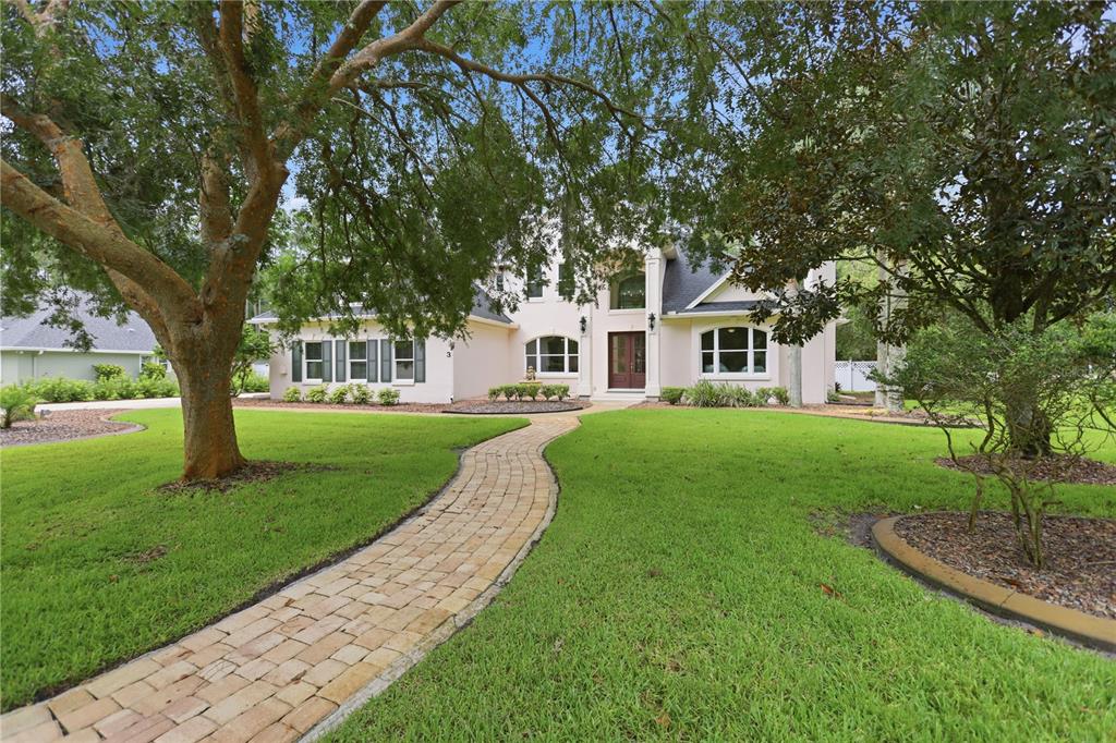 A two-story house with a stone walkway leading to the front door and large trees — 3 ALLENWOOD LOOK, ORMOND BEACH, FL