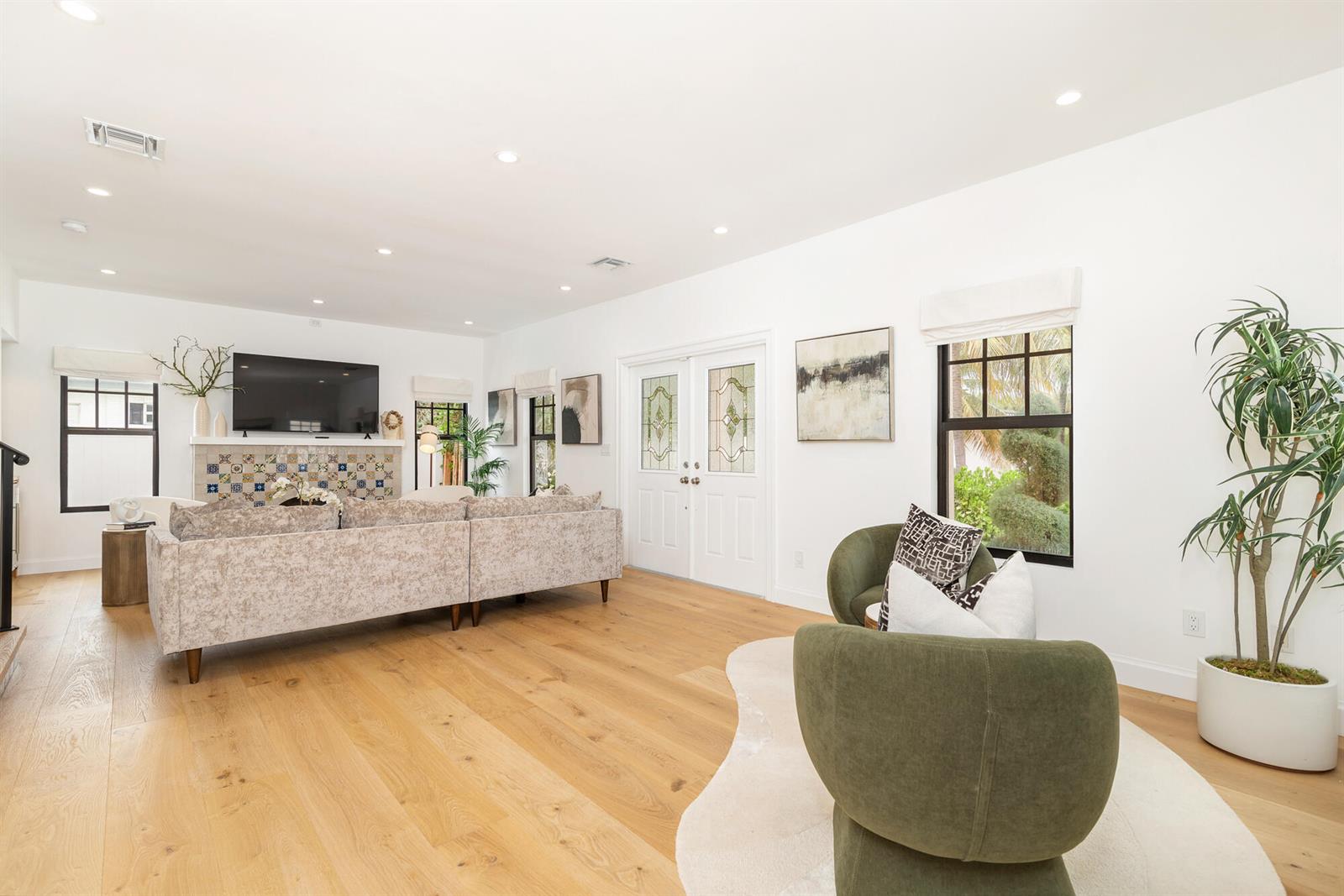 A bright living room features light wood floors, a tiled fireplace, and two green armchairs — 254 9th Street, West Palm Beach FL 33401, WEST PALM BEACH, FL