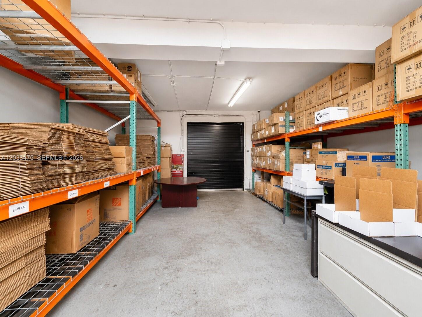 A storage room features metal shelving units filled with cardboard boxes and a central table — 7025 NW 7th Ave, Miami FL 33150, MIAMI, FL