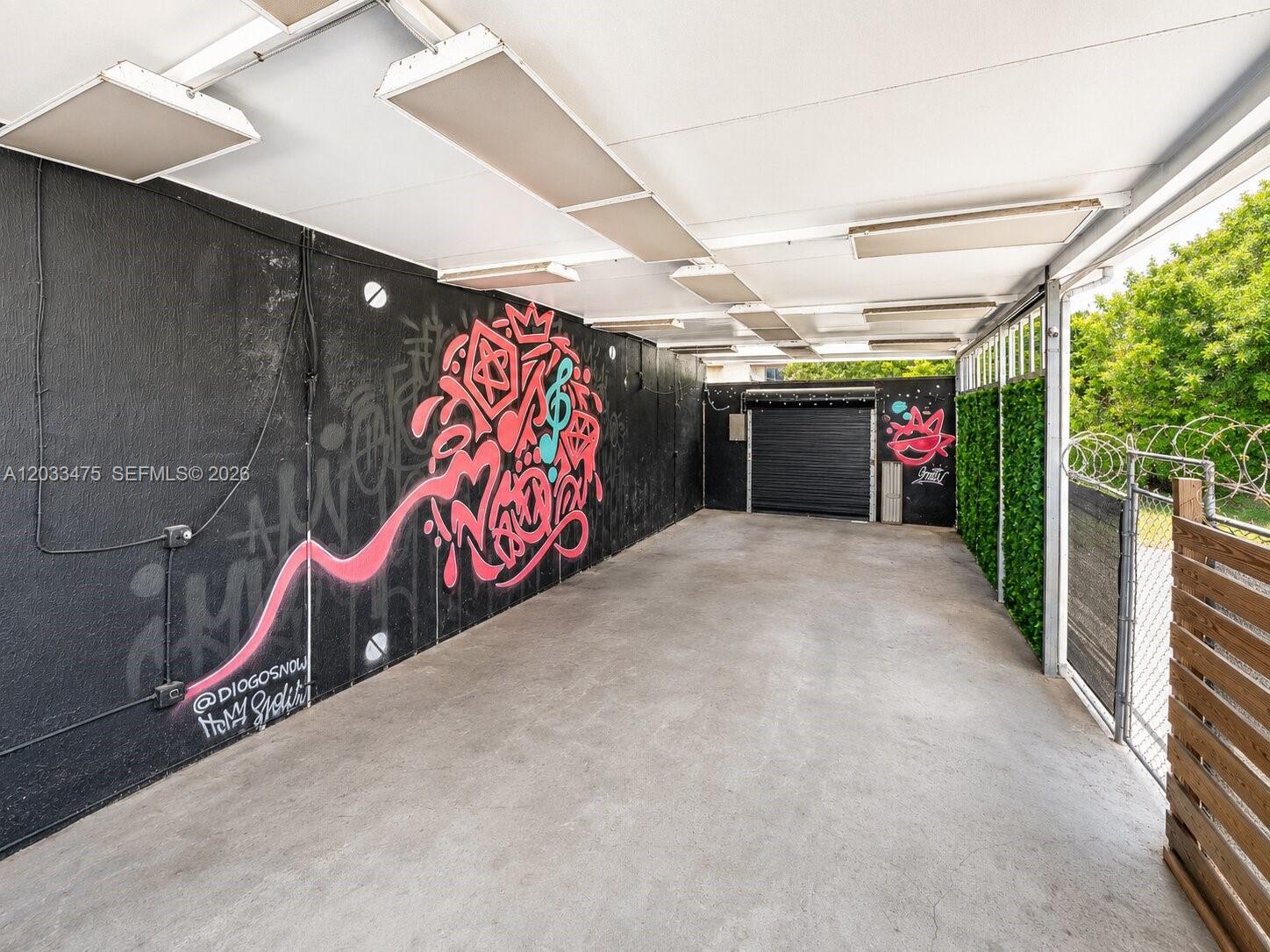 A covered outdoor area features a black wall with graffiti art and a concrete floor — 7025 NW 7th Ave, Miami FL 33150, MIAMI, FL