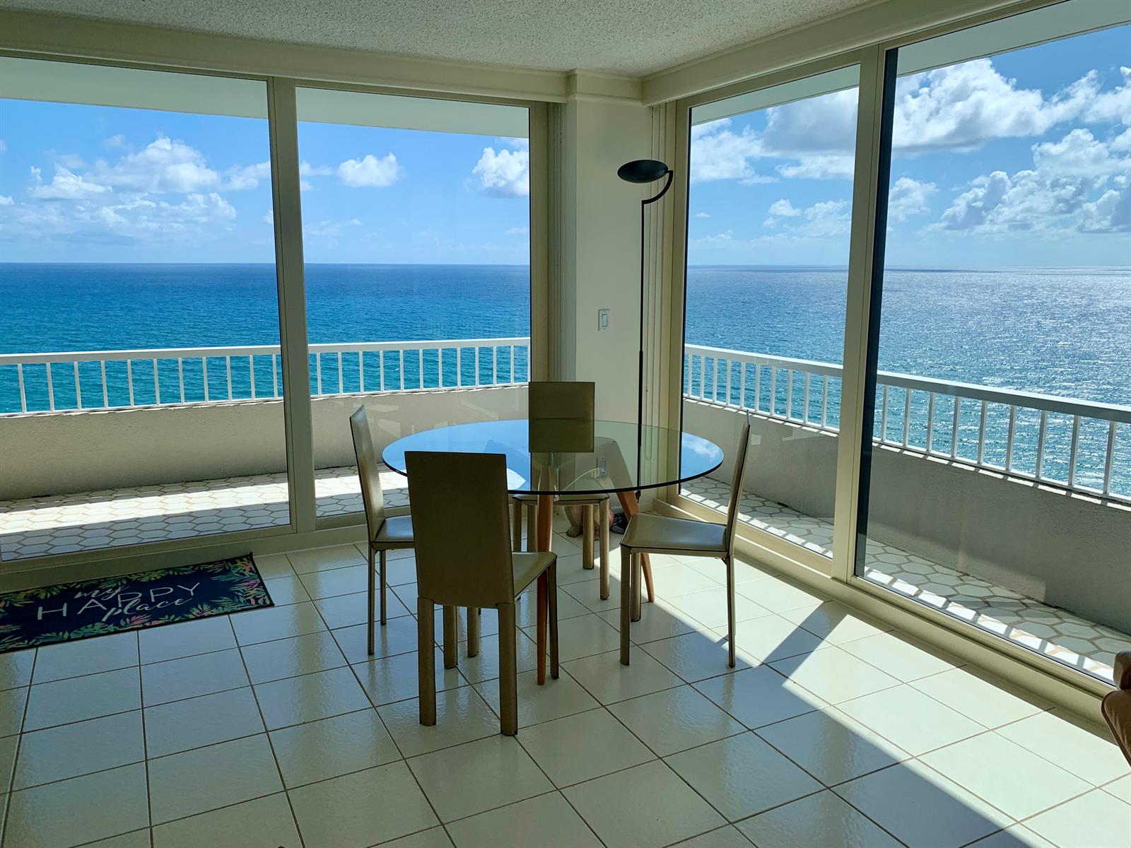 A dining area with a glass table and chairs overlooks the ocean through floor-to-ceiling windows — 5540 N Ocean Drive # a, Riviera Beach FL 33404, RIVIERA BEACH, FL