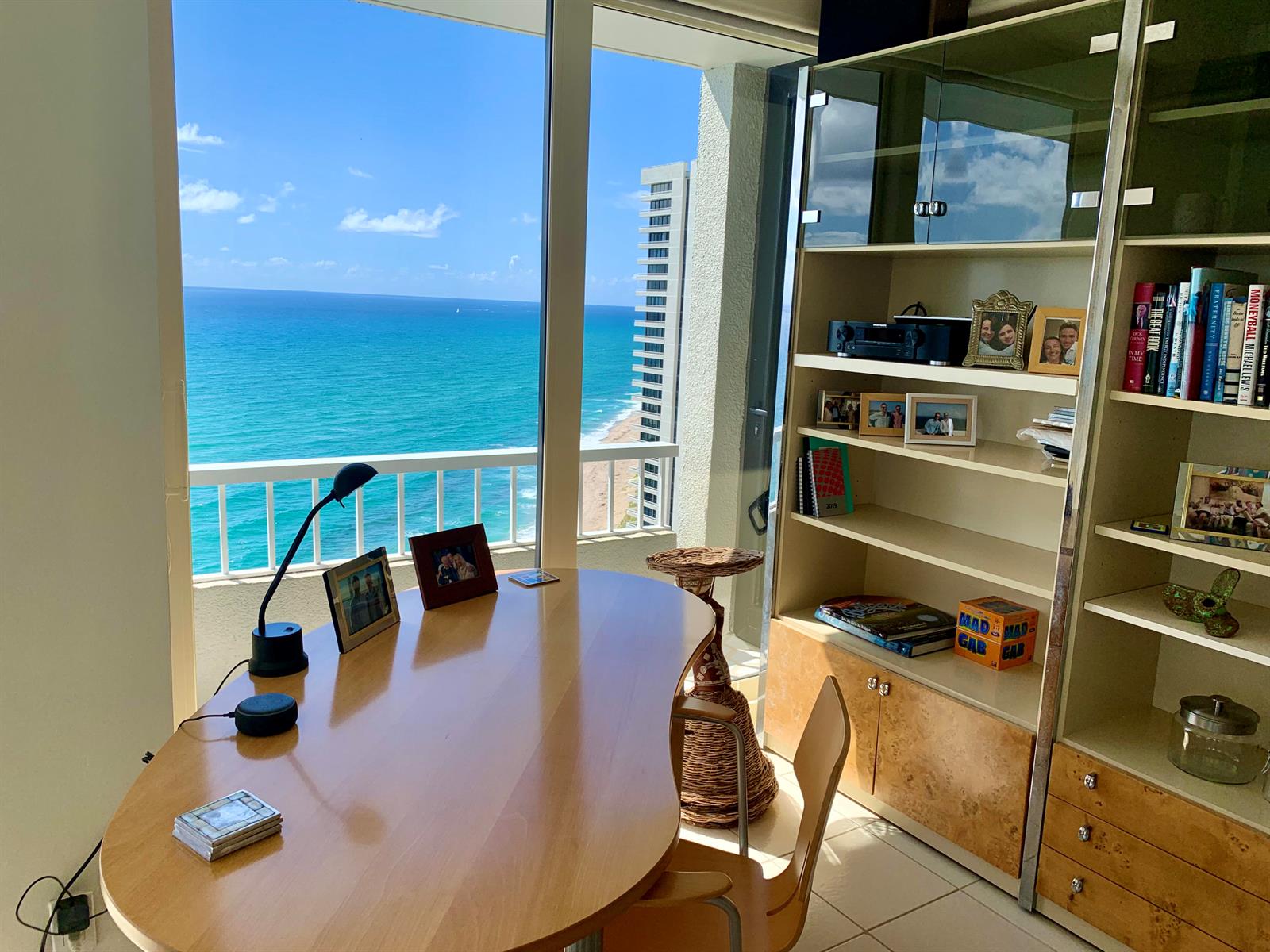 A home office features a kidney-shaped desk, a tall bookshelf, and a view of the ocean — 5540 N Ocean Drive # a, Riviera Beach FL 33404, RIVIERA BEACH, FL