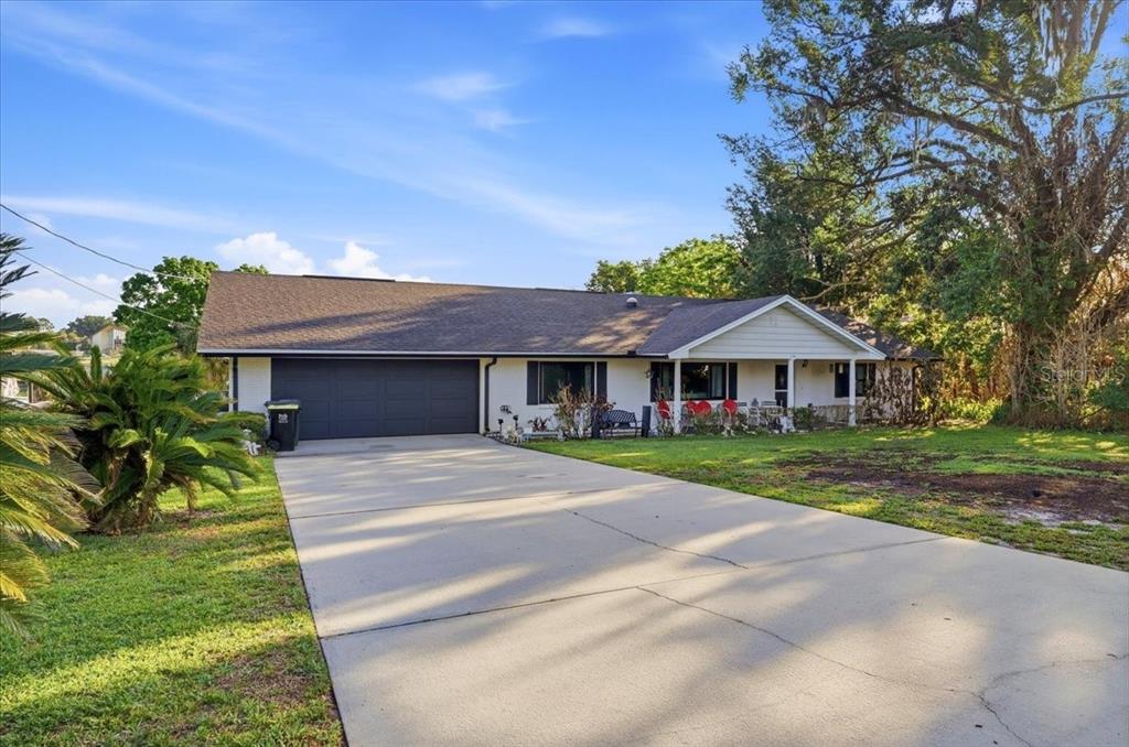 A single-story house with a dark garage door, white siding, and a concrete driveway — 236 W LAKE INA DRIVE, WINTER HAVEN, FL