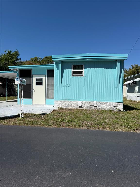 A light blue mobile home with a white door and a stone-textured base — 7803 46TH AVENUE N UNIT 129, ST PETERSBURG, FL