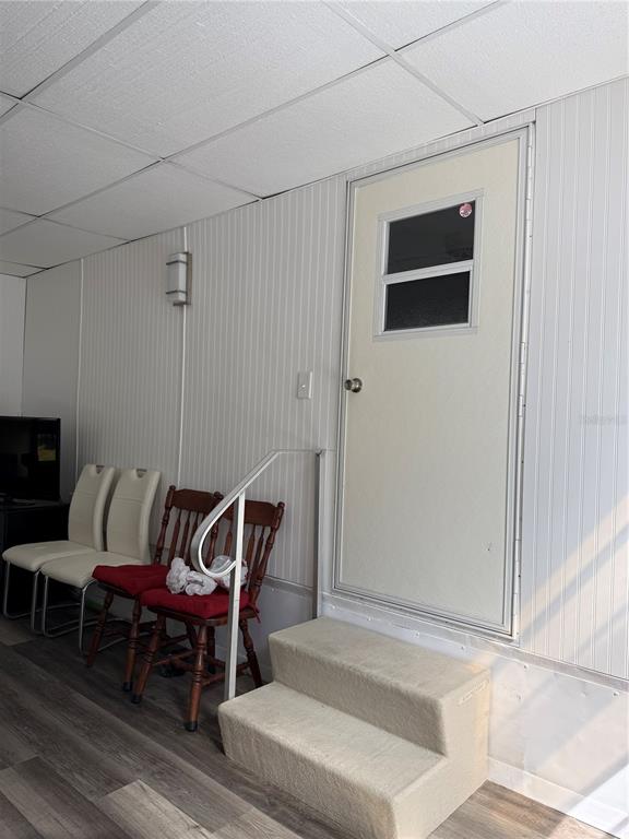 A room with white paneled walls, a door with a window, and two sets of chairs — 7803 46TH AVENUE N UNIT 129, ST PETERSBURG, FL