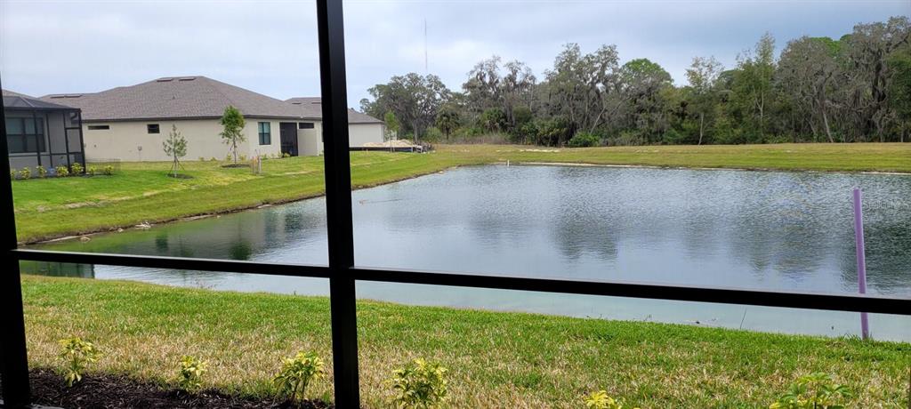 A view of a retention pond and neighboring houses seen through a screened-in porch — 2168 GARDENIA AVENUE, PORT CHARLOTTE, FL