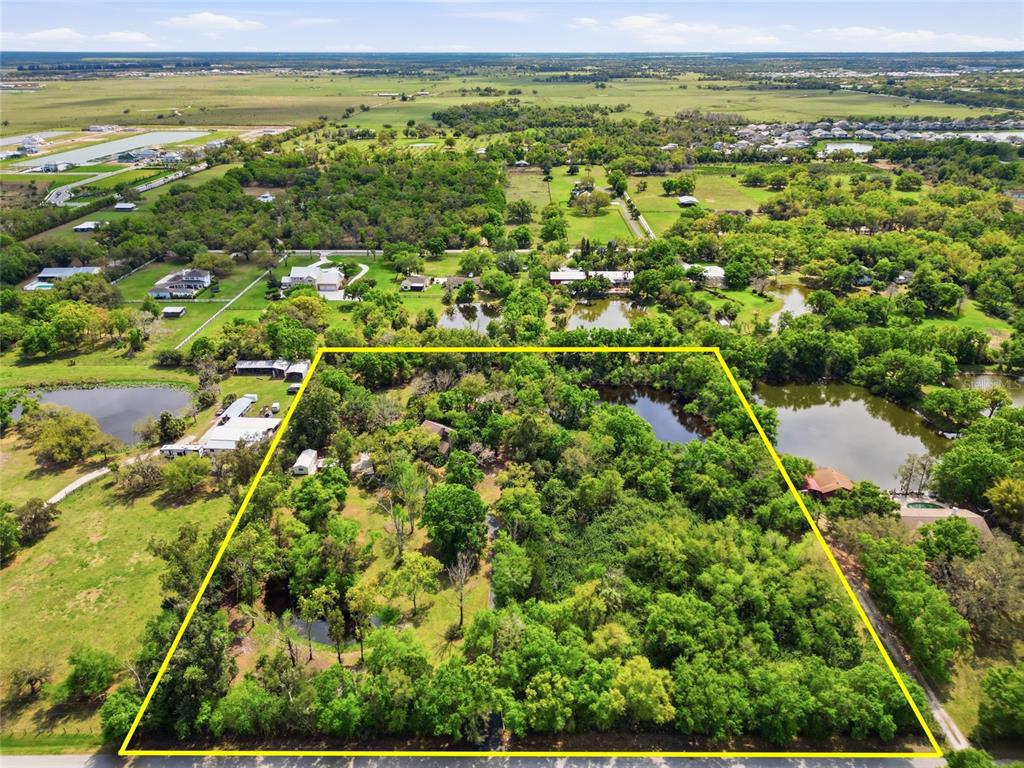 An aerial view shows a wooded lot outlined in yellow with several small ponds — 7336 CURLEW STREET, SARASOTA, FL