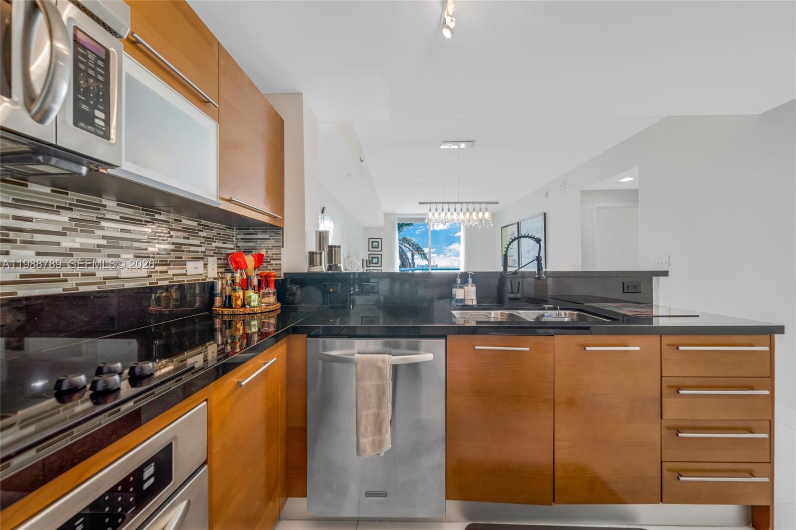 A modern kitchen features wood cabinets, black granite countertops, and stainless steel appliances — 253 NE 2nd St # 1109, Miami FL 33132, MIAMI, FL