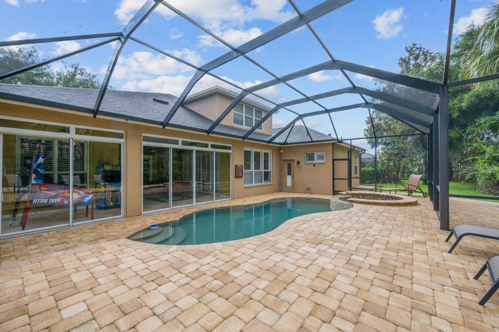 A screened-in patio features a swimming pool, a hot tub, and tan paver flooring — 6122 KESTRELPARK DRIVE, LITHIA, FL