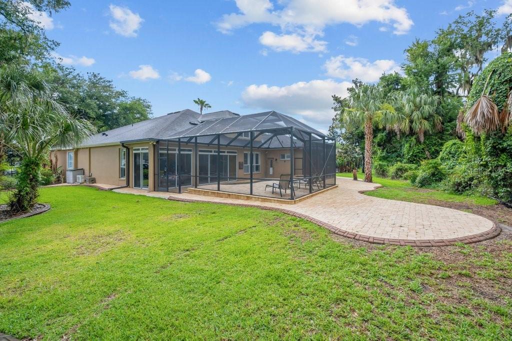 The backyard features a screened-in patio, a paved walkway, and a grassy lawn — 6122 KESTRELPARK DRIVE, LITHIA, FL
