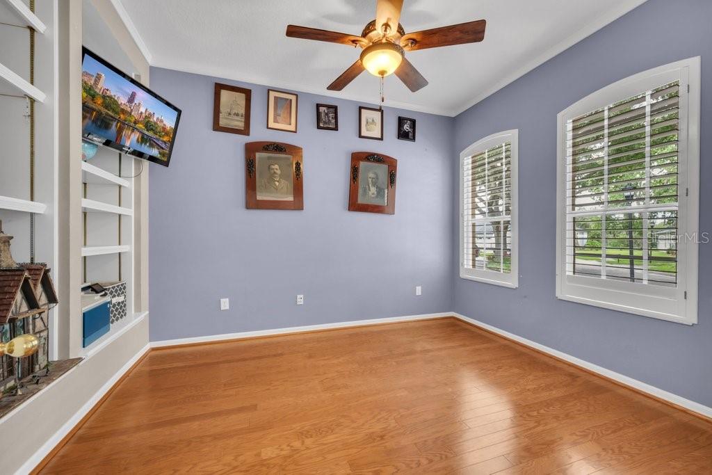 A room with light blue walls, hardwood floors, a ceiling fan, and framed wall art — 6122 KESTRELPARK DRIVE, LITHIA, FL