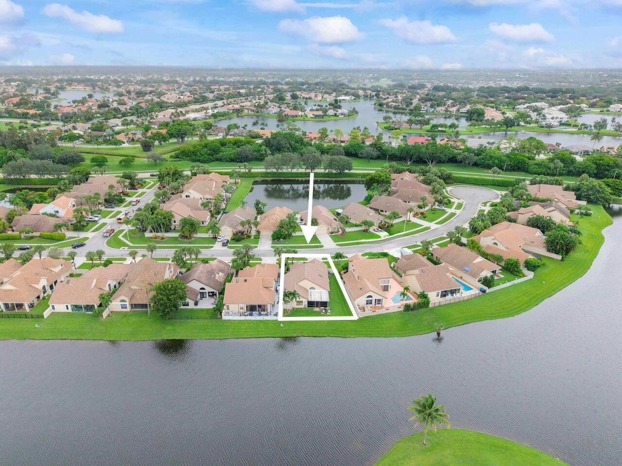 An aerial view shows a residential house with a screened pool enclosure on a lake — 6852 Bitterbush Place, Boynton Beach FL 33472, BOYNTON BEACH, FL