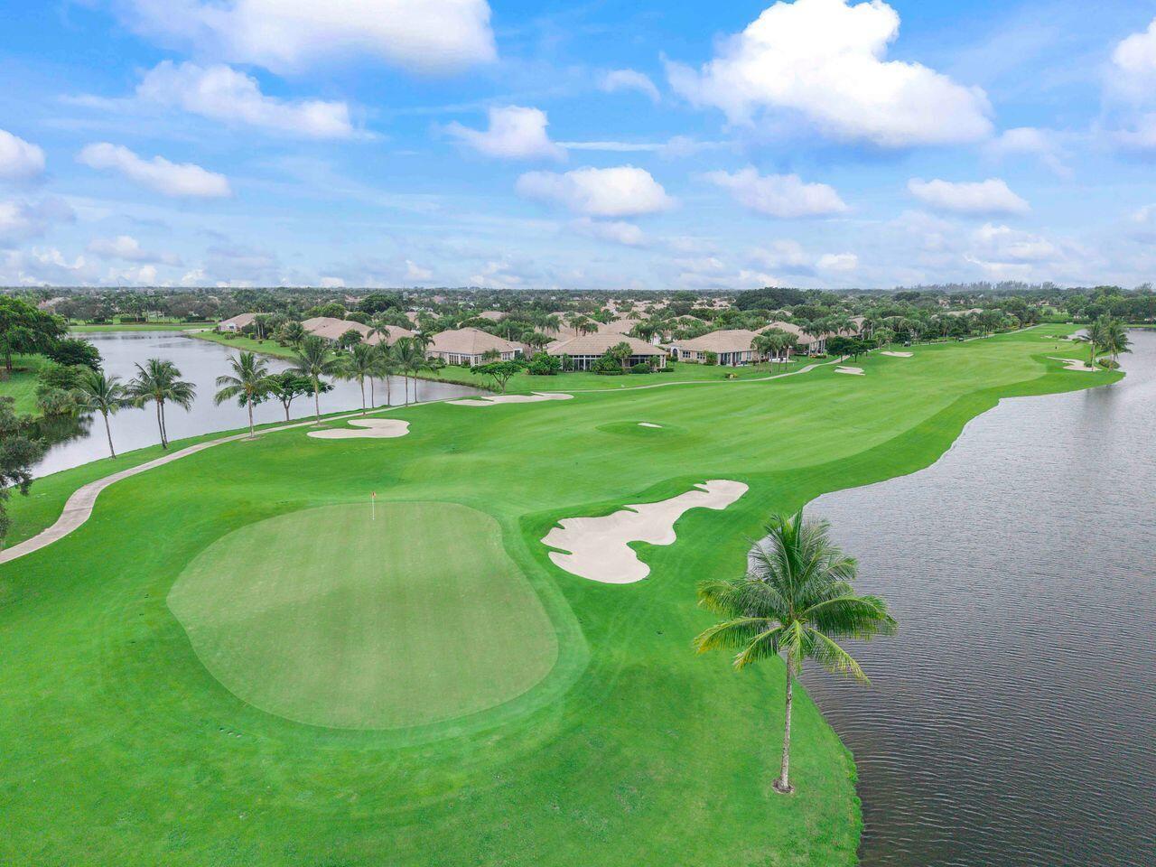 An aerial view of a golf course green with a sand bunker and surrounding water — 6852 Bitterbush Place, Boynton Beach FL 33472, BOYNTON BEACH, FL