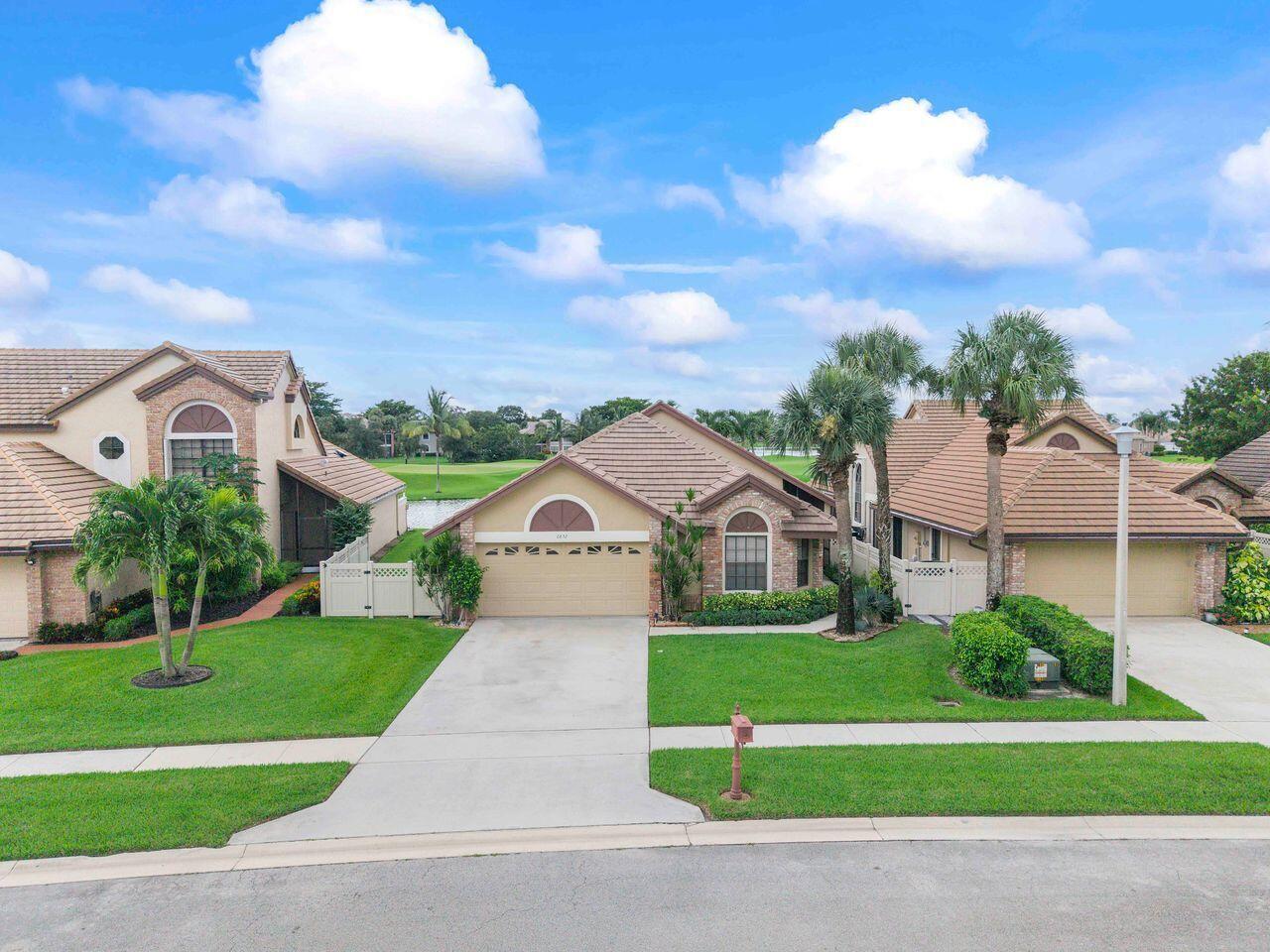 A single-story suburban house with a tan garage, tile roof, and green lawn — 6852 Bitterbush Place, Boynton Beach FL 33472, BOYNTON BEACH, FL