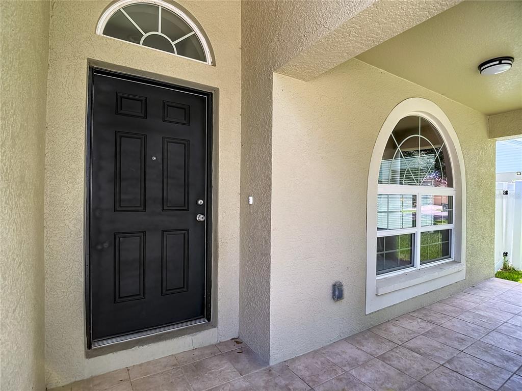 A black front door with a transom window sits beside an arched window on a porch — 805 LESA GLEN PLACE, BRANDON, FL