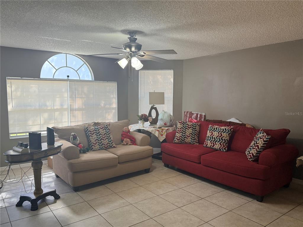 A living room features tile flooring, a ceiling fan, and two sofas facing each other — 2725 N POINCIANA BOULEVARD UNIT 147, KISSIMMEE, FL