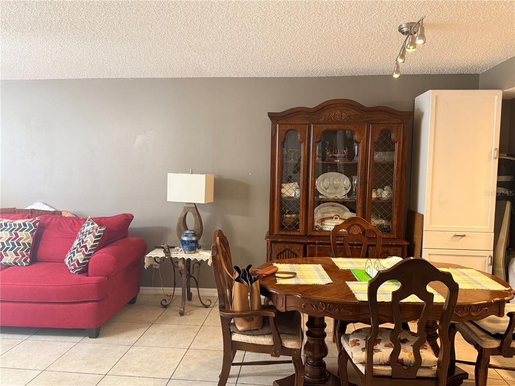 A dining area with a wooden hutch and table sits beside a red sofa — 2725 N POINCIANA BOULEVARD UNIT 147, KISSIMMEE, FL