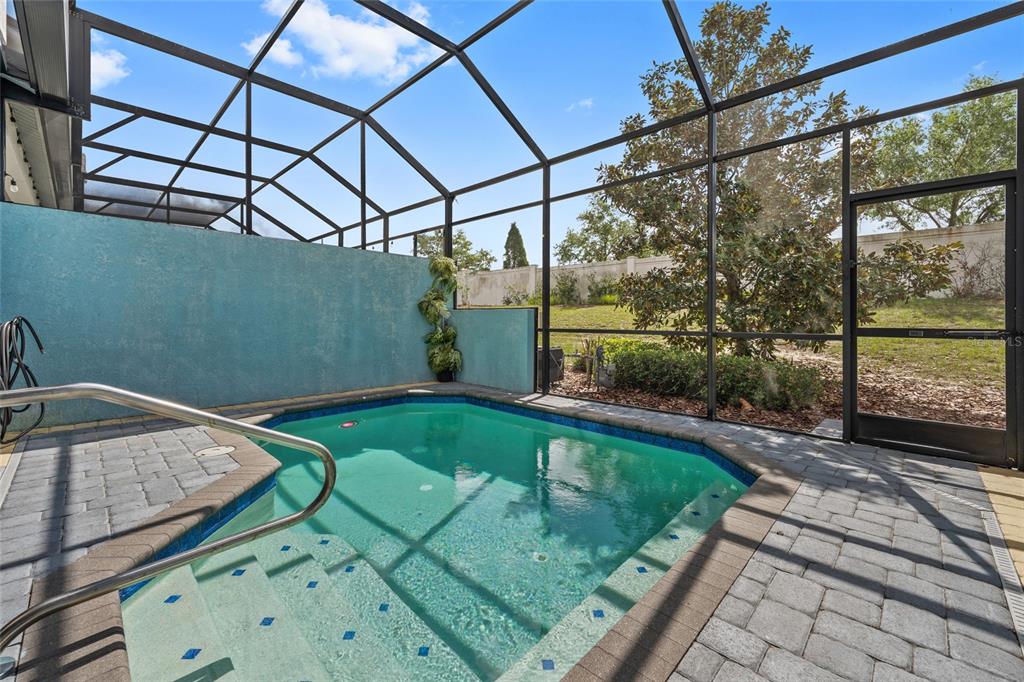 A small swimming pool with steps is enclosed by a screened-in patio and blue walls — 318 CAPTIVA DRIVE, DAVENPORT, FL