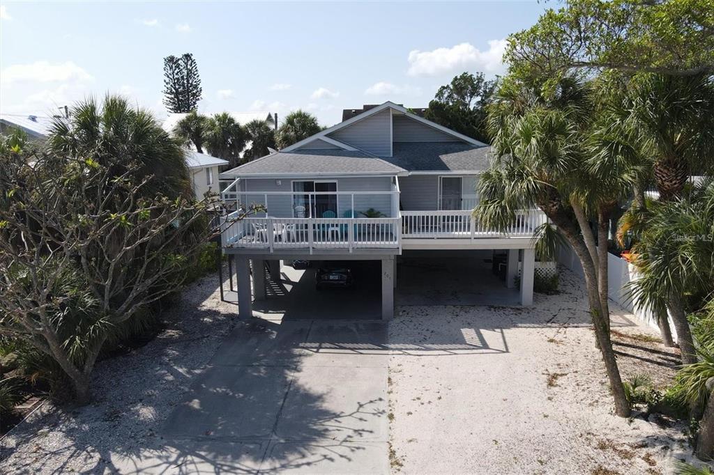 An elevated gray house with a white deck and a covered parking area underneath — 207 71ST STREET UNIT E, HOLMES BEACH, FL