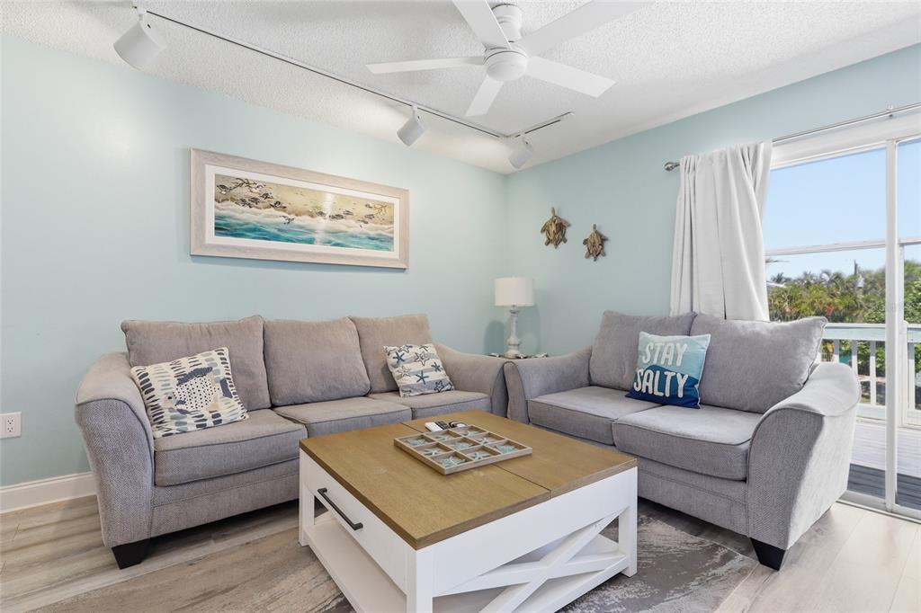 A living room features two gray sofas, a wooden coffee table, and light blue walls — 207 71ST STREET UNIT E, HOLMES BEACH, FL