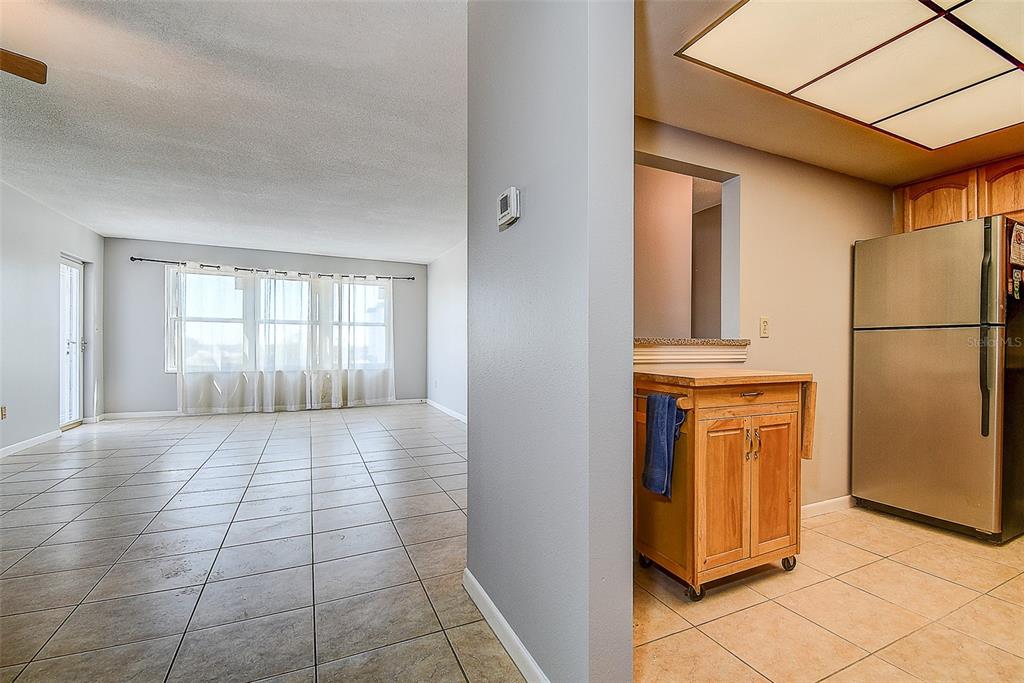 A view from a tiled kitchen looking into an open living area with large windows — 5220 BRITTANY DRIVE S UNIT 509, ST PETERSBURG, FL