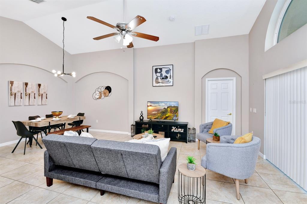 A living and dining area with vaulted ceilings, tile floors, and a ceiling fan — 4661 CUMBRIAN LAKES DRIVE, KISSIMMEE, FL