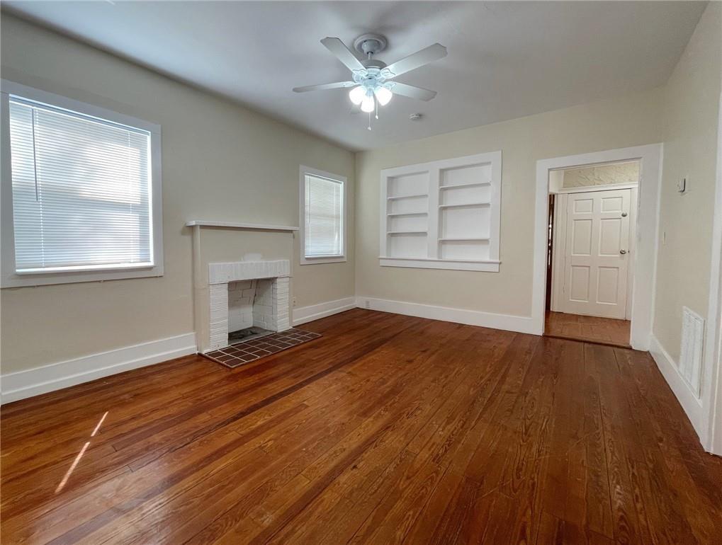 A living room features hardwood floors, a white brick fireplace, and built-in wall shelving — 1969 NE 4th Street, Deerfield Beach FL 33441, DEERFIELD BEACH, FL