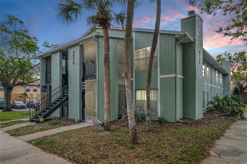 A two-story apartment building with green stucco siding, a metal staircase, and palm trees — 4830 S SEMORAN BOULEVARD UNIT 1108, ORLANDO, FL