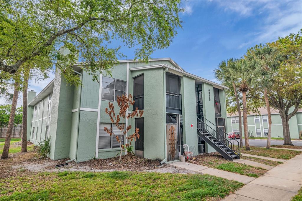 A two-story light green apartment building features exterior staircases and screened-in balconies — 4830 S SEMORAN BOULEVARD UNIT 1108, ORLANDO, FL