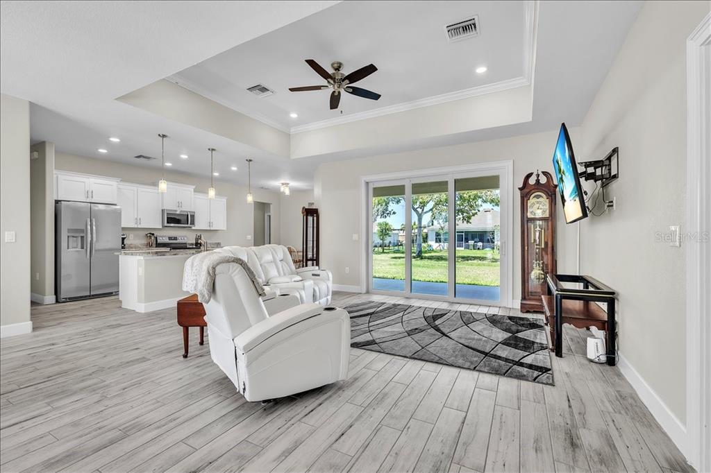 A living room with white tile floors, a tray ceiling, and a view of the backyard — 16047 DINAL DRIVE, PUNTA GORDA, FL