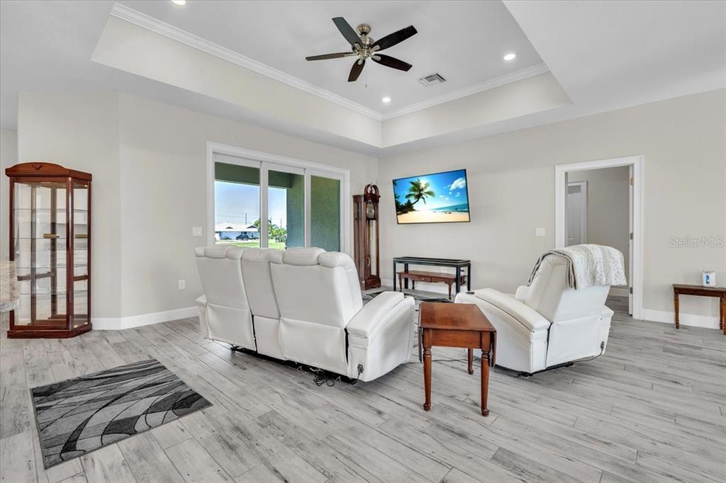 A living room features white leather furniture, a tray ceiling, and light wood-look flooring — 16047 DINAL DRIVE, PUNTA GORDA, FL