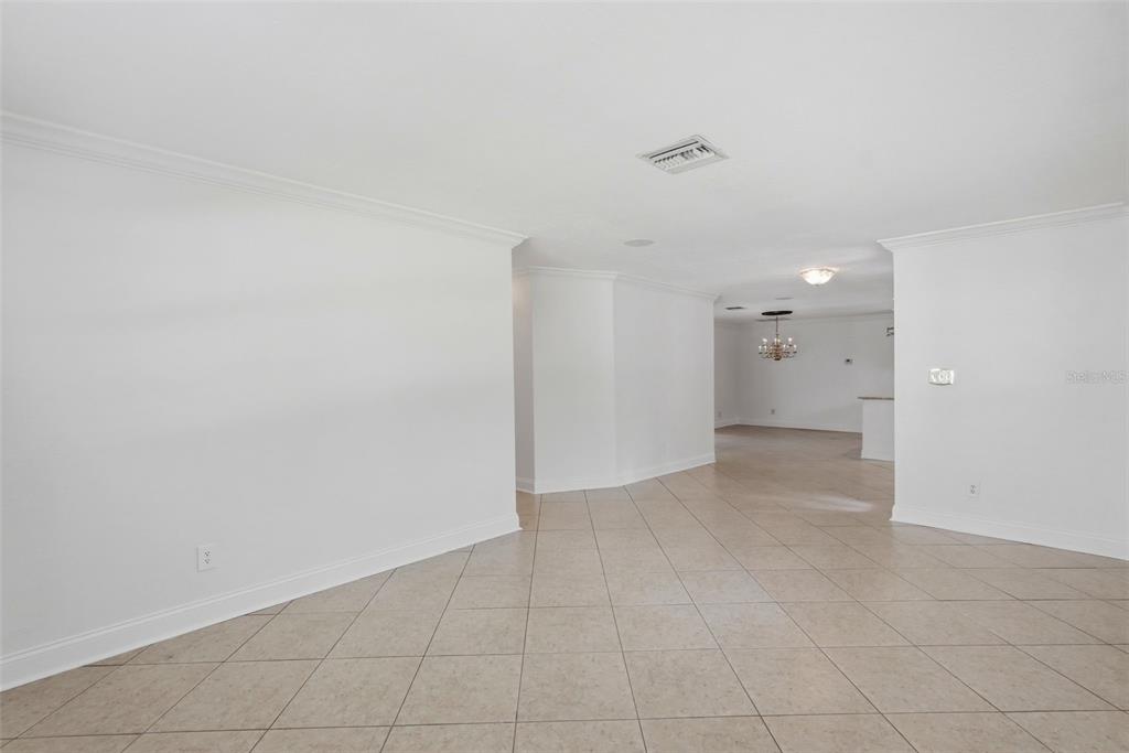 An interior view of a room with white walls, crown molding, and beige tile flooring — 8235 39TH AVENUE N, ST PETERSBURG, FL