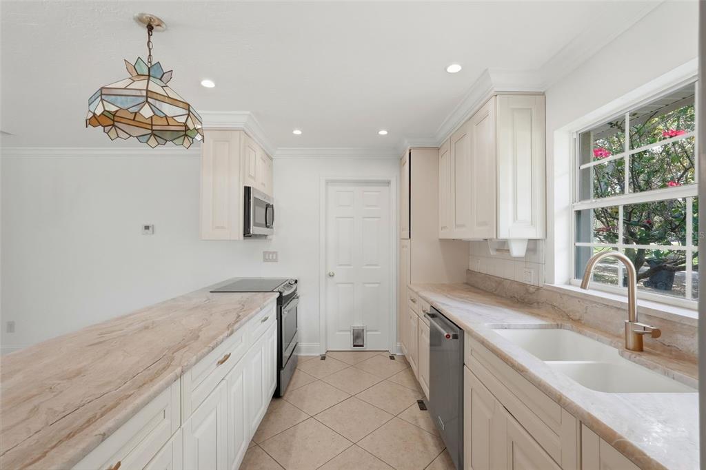A kitchen with white cabinets, light stone countertops, a stained-glass pendant light, and tile flooring — 8235 39TH AVENUE N, ST PETERSBURG, FL