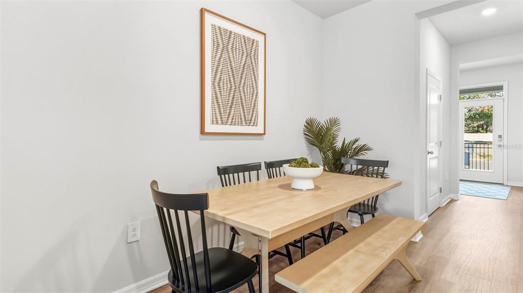 A dining area features a light wood table, black chairs, a bench, and wall art — 4052 GOLD DUST LANE, SARASOTA, FL
