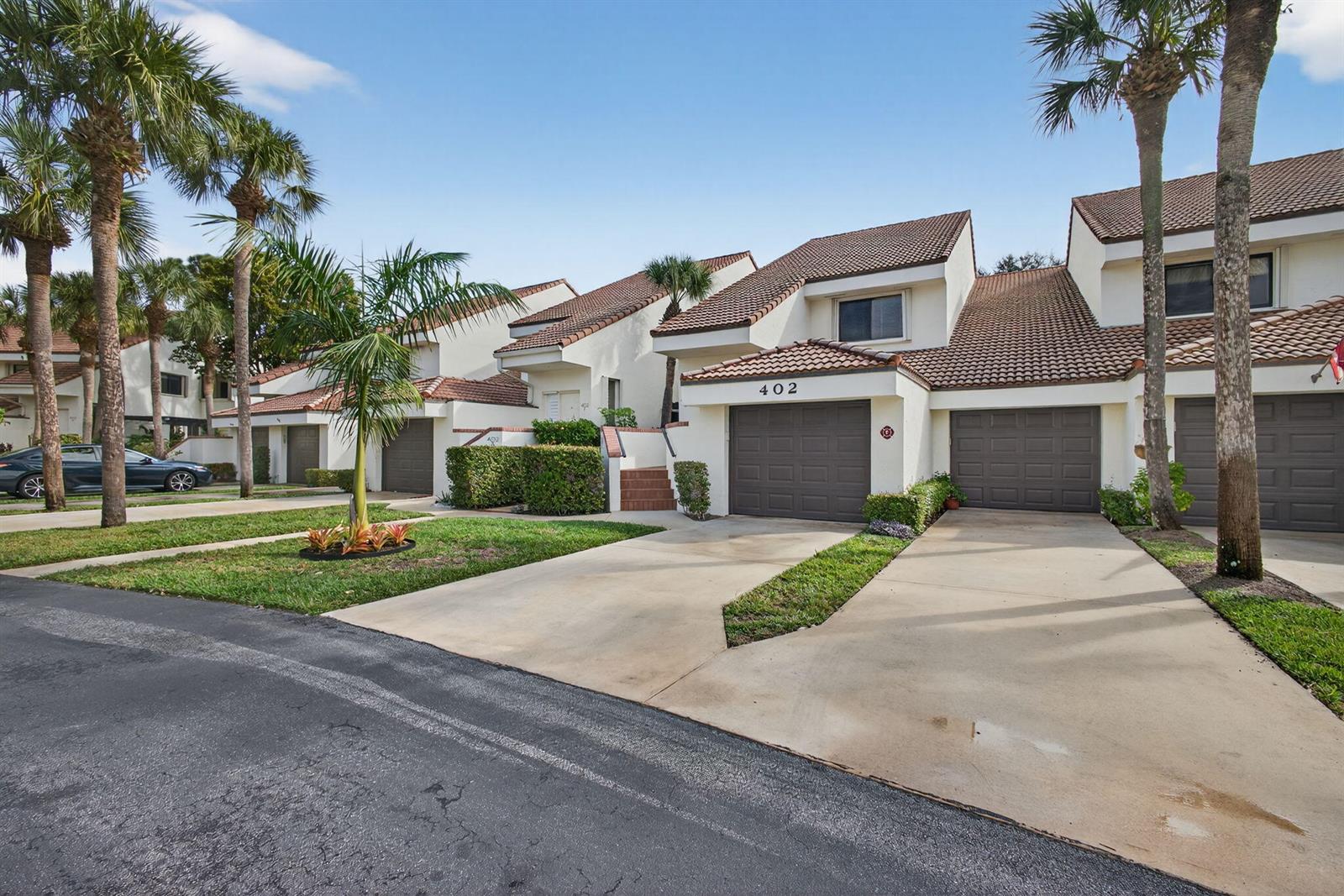 A row of townhouses with brown garage doors, tiled roofs, and palm trees in the front — 402 Sea Oats Drive # G, Juno Beach FL 33408, JUNO BEACH, FL