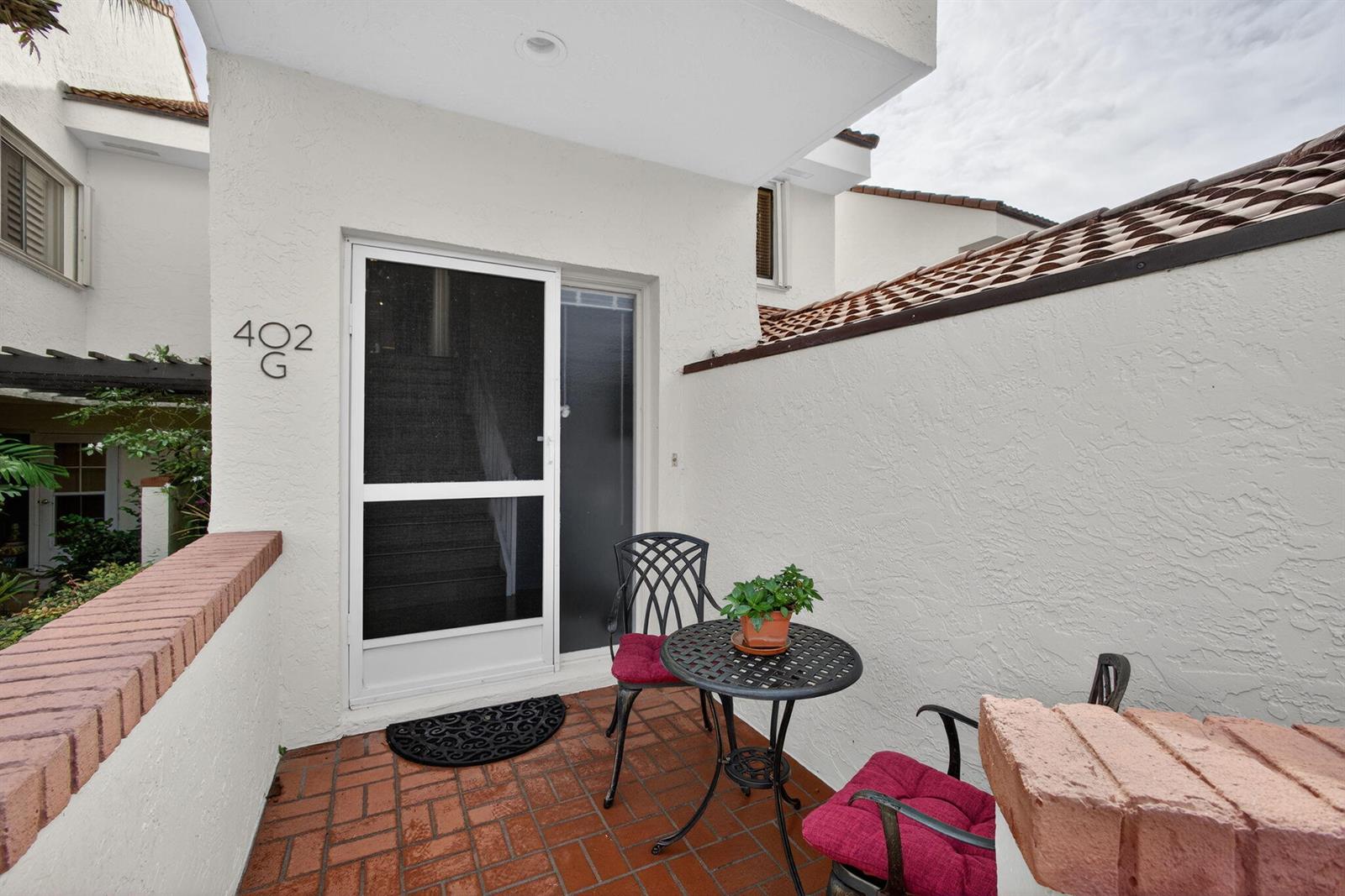 A small patio with a brick floor, a bistro set, and a screen door entrance — 402 Sea Oats Drive # G, Juno Beach FL 33408, JUNO BEACH, FL